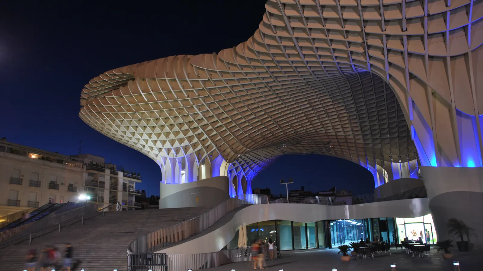 The Metropol Parasol at night, its timber lattice lit above the glazed ground floor and the wide stairs of Plaza de la Encarnación